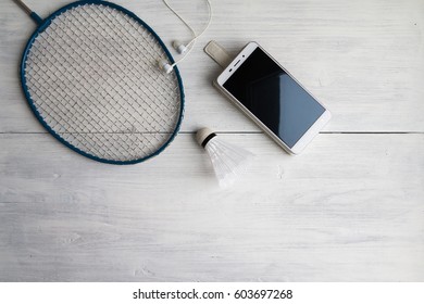 Still Life - Active Lifestyle Concept - Shuttlecock, Mobile Phone, Earphones On White Wooden Table. Top View.