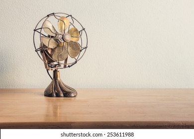 still life with antique fan on wooden table over grunge background