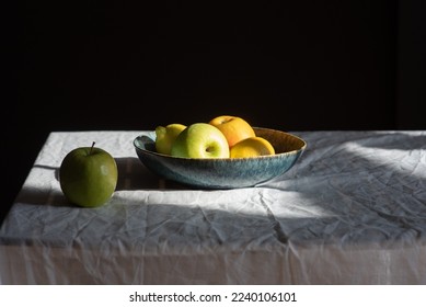 Still life with apples and lemons in a blue clay bowl on a wrinkled linen tablecloth - Shutterstock ID 2240106101