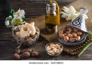 Still Life Of Argan Oil And Fruit And Shea Butter With Nuts On A Wooden Table With Flowers