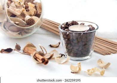 Still Life With Aroma Candle In The Glass With Coffee Beans, Cinnamon, Perfume Sticks And Ornamental Dried Flowers Setting