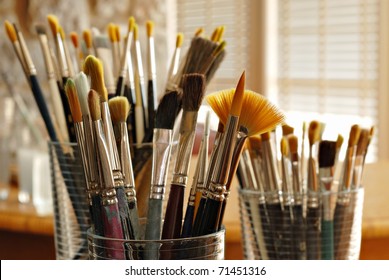 Still life of artist's brushes in sunlit studio.  Closeup with shallow dof.  Selective focus on fan brush. - Powered by Shutterstock