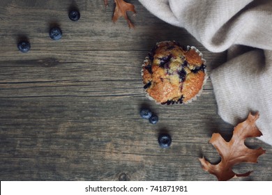 Still Life With Blueberry Muffin, Warm Blanket, Leaves And Blueberries Over Rustic Wooden Background Shot From Directly Above, Copy Space, Horizontal