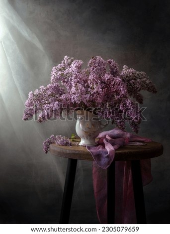 Still life with a bouquet of lilacs on a wooden table near the window.
