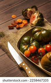still life with cherry tomatoes, large ripe sweet marmalade tomatoes, carrot slices and a knife on burlap cloth - Shutterstock ID 2258467335