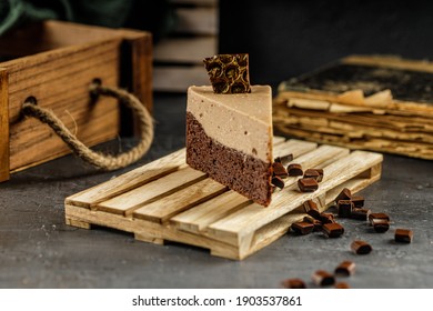 Still Life Of Chestnut Cake With Chocolate Mousse On A Dark Gray Table With Chocolate Pieces.