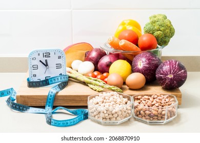 Still Life With A Clock, A Tape Measure And Healthy Food. Conceptual Image Of Intermittent Fasting, A Diet With Benefits Such As The Regenerative Mechanism Of Autophagy.