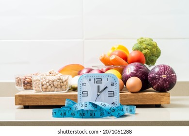 Still Life With A Clock, A Tape Measure And Healthy Food. Conceptual Image Of Intermittent Fasting, A Diet With Benefits Such As The Regenerative Mechanism Of Autophagy.