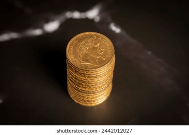 Still life. Close-up view stack of golden Louis coins on a black and white marble surface