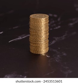 Still life. Close-up view stack of golden Louis coins on a black and white marble surface