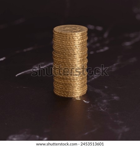 Still life. Close-up view stack of golden Louis coins on a black and white marble surface