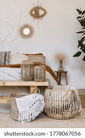 Still Life Concept. Vertical Photo Of Cozy Apartment In Boho Chic Style Interior With Comfort Bedroom, Fabric Sheet Plaid On Bed, Wooden Bench Seat, Dry Plants In Vase, Home Decor In Wicker Basket