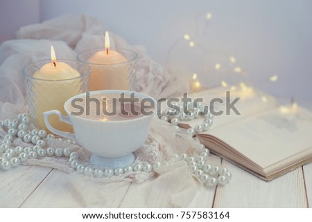 still life with Cup of coffee, candles, book, pearl beads on wooden table. romantic mood atmosphere, vintage style. symbol of  love, romance and tenderness.