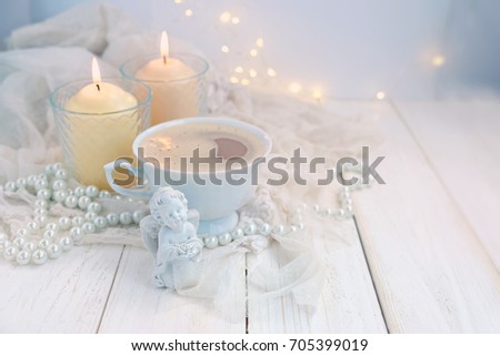still life with Cup of coffee, figurine angel, candles and pearl beads on table close up, abstract light background. symbol of  love, romance and tenderness. Valentine's day greeting card design.