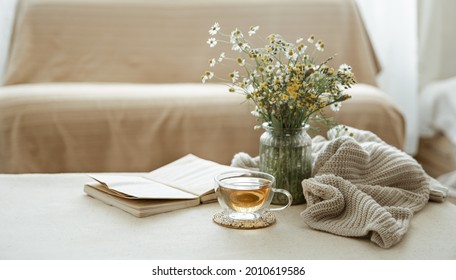 Still life with a cup of herbal tea, a bouquet of wildflowers, a book and a knitted element. - Powered by Shutterstock