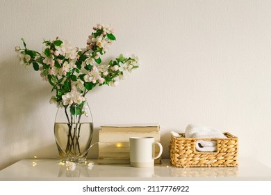 Still life details in home interior of living room. Book, candle and vase with apple spring flowers. Read and rest. Cozy spring concept.