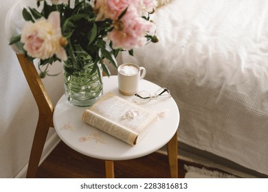 Still life details in home interior of living room. Open book with glasses, cup coffee and bouquet white pink peonies flowers. Read and rest. Cozy home - Powered by Shutterstock