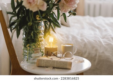 Still life details in home interior of living room. Open book with glasses, cup coffee and bouquet white pink peonies flowers. Read and rest. Cozy home - Shutterstock ID 2283816825