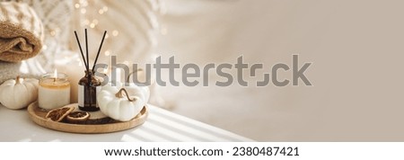 Still life details in the living room. Autumn composition with aroma diffuser with pumpkin pie scent, knitted sweaters, candles. Concept of slow life, relaxation, detention. Apartment decor banner