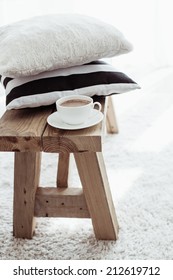 Still life details, stack of black and white cushions on rustic bench on white carpet