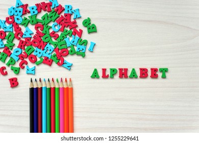 Still life of developing objects for children's creativity and hobbies of adults, wooden multicolored letters of the alphabet, colored pencils on a wooden background - Powered by Shutterstock