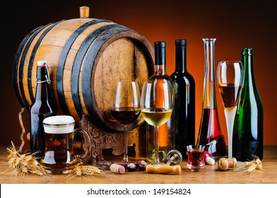 still life with different alcoholic drinks and wooden barrel
