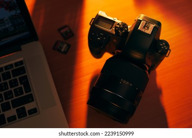 Still life of dslr camera, sdhc flash memories and laptop computer on wooden table. High angle view of objects with sunset lighting