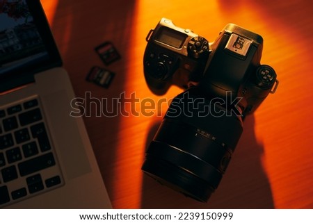 Still life of dslr camera, sdhc flash memories and laptop computer on wooden table. High angle view of objects with sunset lighting