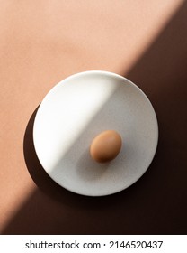 Still Life With An Egg On A Plate. Photos In Natural Colors. Minimal Food Concept. Dramatic Light And Shadows