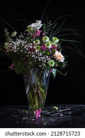 Still life of a flower bouquet in vase with vintage scissors on talbe in dark and moody tone with black background