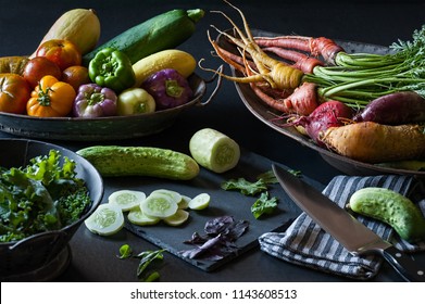 A still life of fresh summer produce from the garden including cucumber, carrots, peppers and more.