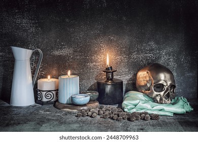 A still life with a golden skull on a green satin cloth next to several lit candles - Powered by Shutterstock