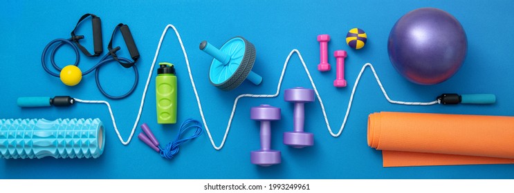 still life of group sports equipment for womens and cardiogram of jump rope, on blue background. Fitness and healthy living, wellness concept.