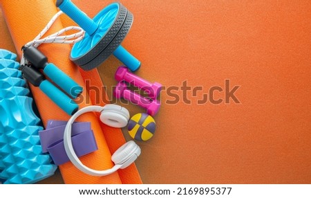 still life of group sports fit equipment for womens, on orange background. Fitness concept with empty space for text, top view