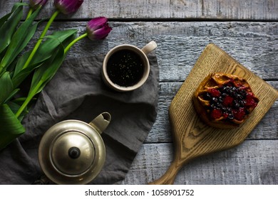 Still life with herbal tea, bun with berries and tulips on grey wooden background - Powered by Shutterstock