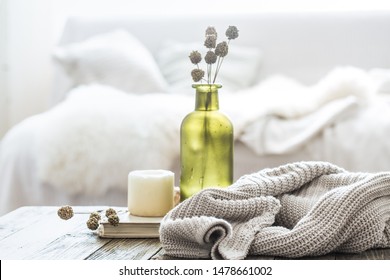 Still life home decor on a wooden table in the living room. decorative bottle with flowers and a candle near a knitted sweater. - Shutterstock ID 1478661002