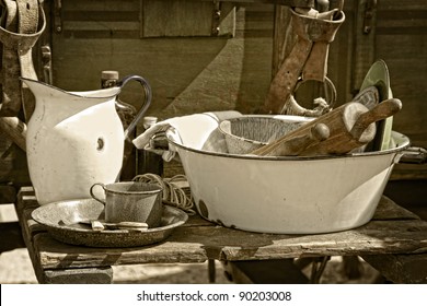 Still Life Image Of Vintage Cooking Utensils And Dishes Beside An Authentic American Old West Style Chuck Wagon At An Outdoor Cooking Demonstration (sepia Tint Added).