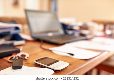 Still Life Images Of A Busy Entrepreneur's Desk In Their Home Office Space, With Technology And Paperwork Cluttering The Table Space