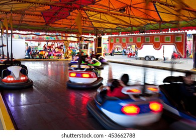 Still life intense view of a fun park bumper cars ride under colorful marquee, sunny day. Active bumper cars motion blur entertainment in fun amusement park, funfair rides moving fast bright lights.