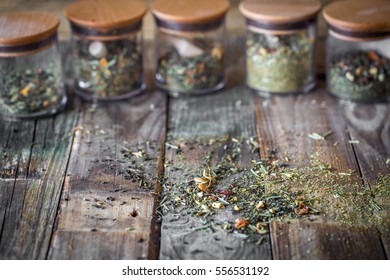 Still Life Of Loose Tea In Glass Jar And Wooden Spoons On Wooden Background