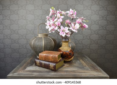 Still life with Magnolia blossom, old books and lantern on rustic wooden table.