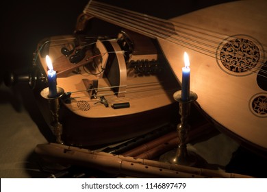 Still life with medieval musical instruments, lute, flutes, hurdy-gurdy and tambourines and candles