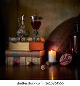 Still life with old books, a burning candle, lute and pomegranate              - Shutterstock ID 1615264555