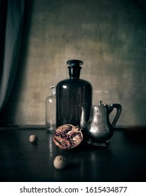 Still life with the old glass bottles, silver teapot and pomegranate. - Shutterstock ID 1615434877