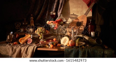 Still life in old masters style with lobster, glass of wine, silver dishes, fruits, guitar lute and hunting horn.            