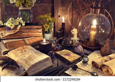 Still life with old-fashioned lamp, magic witch books, tarot cards and old papers. Mystic background with ritual esoteric objects, occult, fortune telling and halloween concept