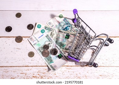 Still Life: On The Table Is A Grocery Cart And Large Russian Money With Coins, The Concept Of Profit