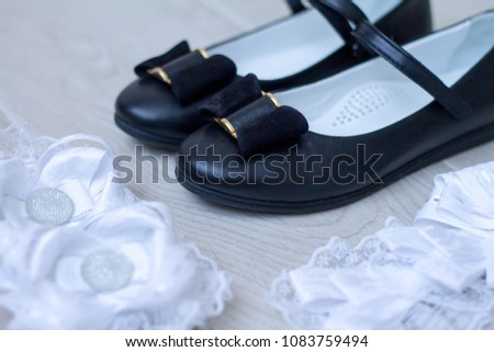 Still Life on a theme back to school: School elegant shoes for a girl and white bows on a wooden floor.