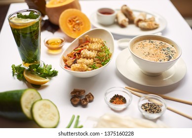 Still life on white tablecloth. Oriental dinner from soup with seeds, tempura shrimps and noodles with vegetables preparing for client. Three dishes lunch with mint tea ready for eating. - Powered by Shutterstock