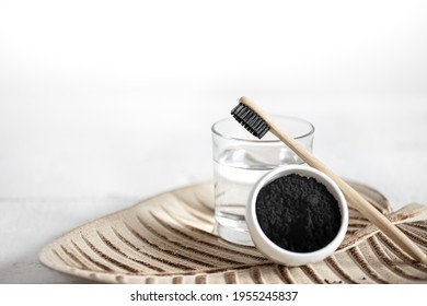 Still life with an organic wooden toothbrush with a glass of water and natural teeth whitening powder. Oral hygiene and dental care.